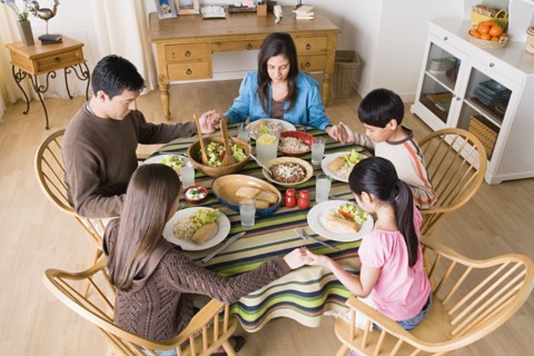Family with three children (8-9, 10-11) praying at table before dining. Photo : Rob Lewine