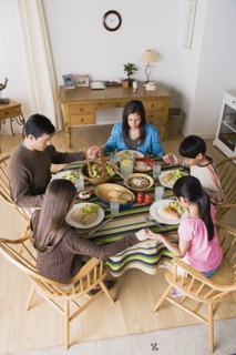Family with three children (8-9, 10-11) praying at table. Photo : Rob Lewine