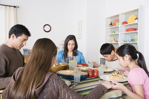 Family with three children (8-9, 10-11) praying at table. Photo : Rob Lewine