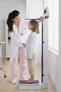 Female doctor measuring girl (4-5). Photo : Rob Lewine