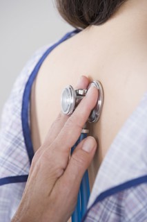 Close up of doctor's hand examining woman with stethoscope. Photo : Rob Lewine