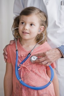 Female doctor with girl (4-5) listening to stethoscope. Photo : Rob Lewine