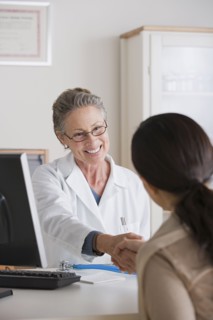 Smiling female doctor shaking hand with patient in her office. Photo : Rob Lewine