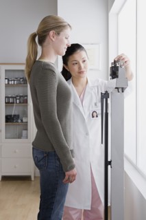 Female doctor measuring woman's weight. Photo : Rob Lewine