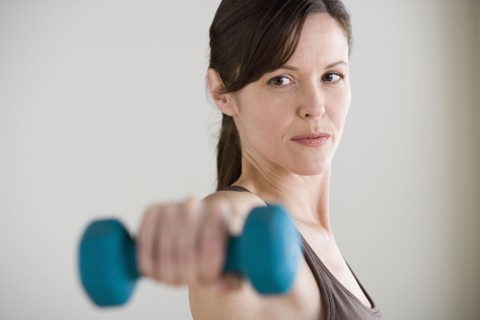 Portrait of woman lifting dumbbell. Photo : Rob Lewine