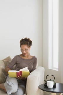 Woman relaxing with book at home. Photo : Rob Lewine