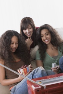 Three female friends watching television. Photo : Rob Lewine