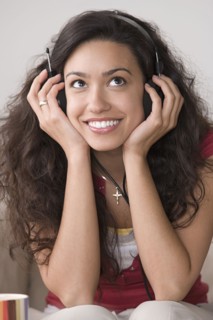 Young woman listening to music and smiling. Photo : Rob Lewine