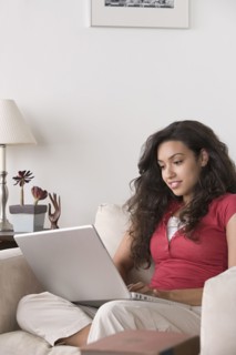 Young woman using laptop at home. Photo : Rob Lewine