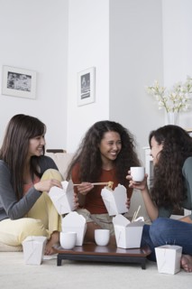 Young women eating take out food at home. Photo : Rob Lewine