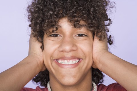 Portrait of teenage boy (14-15) covering ears with hands. Photo : Rob Lewine