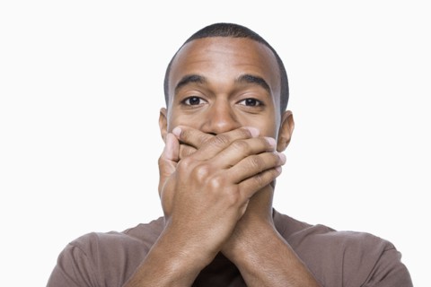 Studio portrait of young man with hands on his mouth. Photo : Rob Lewine