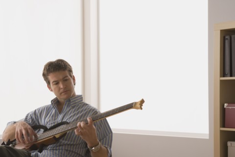 Young man playing electric base guitar. Photo : Rob Lewine