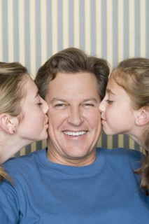 Portrait of father being kissed by two girls (8-9, 14-15) . Photo: Rob Lewine