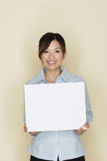 Portrait of happy asian woman holding blank sheet of paper. Photo : Rob Lewine
