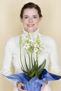 Portrait of smiling woman holding flowers, studio shot. Photo : Rob Lewine