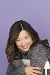Portrait of smiling woman on purple background, studio shot. Photo : Rob Lewine