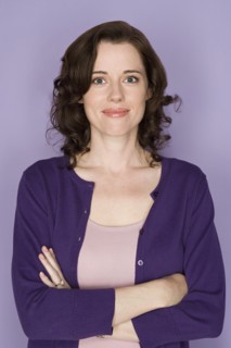 Portrait of smiling woman on purple background, studio shot. Photo : Rob Lewine