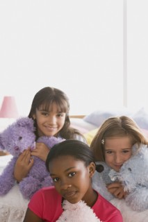 Portrait of three girls (10-11) with puppets in bed. Photo: Rob Lewine