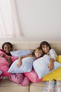 Portrait of three girls (10-11) lying on sofa at slumber party. Photo : Rob Lewine