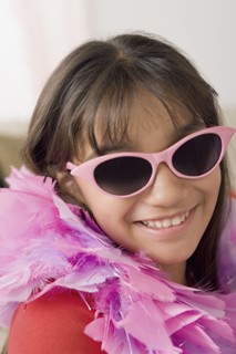Portrait of smiling girl (10-11) wearing feather boa and sunglasses. Photo : Rob Lewine