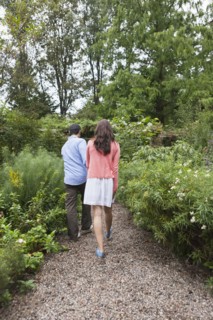 Rear view of couple walking through garden. Photo : Tetra Images