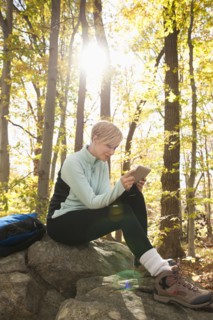 Female hiker using digital tablet in forest. Photo : Tetra Images