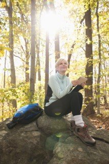 Female hiker using digital tablet in forest. Photo : Tetra Images