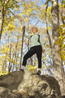 Female hiker resting on rock in forest. Photo: Tetra Images