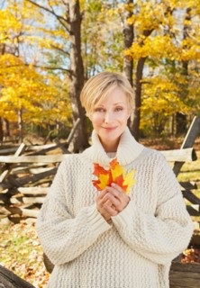 Portrait of smiling woman holding leaves in Autumn forest. Photo : Tetra Images