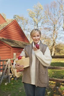 USA, New Jersey, Portrait of smiling woman holding basket with apples in front of cottage house in