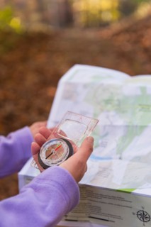 USA, New Jersey, Close-up of woman's hands holding compass and map. Photo : Tetra Images
