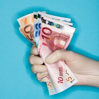 Hand in surgical glove holding banknotes.