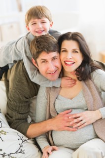 Portrait of parents with son (4-5) on sofa.