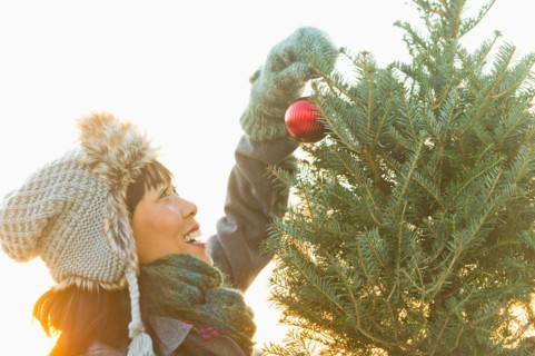 Smiling woman decorating Christmas tree.