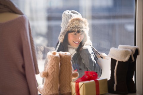 Smiling woman looking at shop display during Christmas shopping.