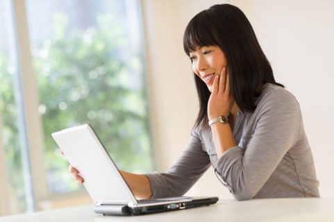 Smiling woman using laptop.