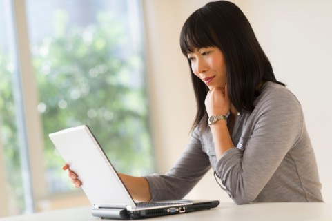 Smiling woman using laptop.