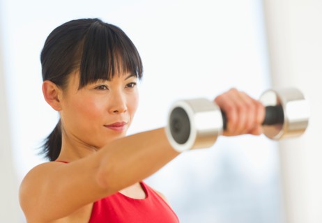 Mid adult woman exercising with dumbbells.