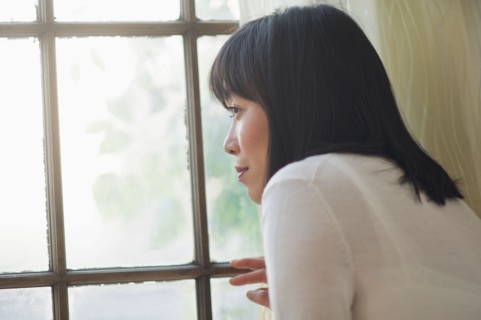 Thoughtful woman looking through window.