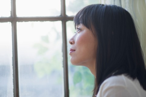 Thoughtful woman looking through window.