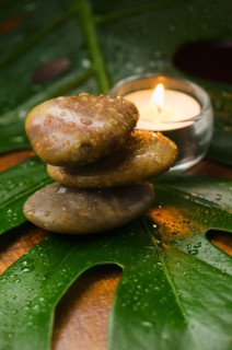 Spa stones and candle on tropical leaf, studio shot.