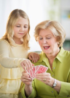 Grandmother with granddaughter (8-9) playing cards.