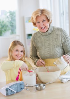 Grandmother with granddaughter (8-9) preparing food.