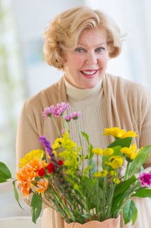 Smiling senior woman arranging flowers.