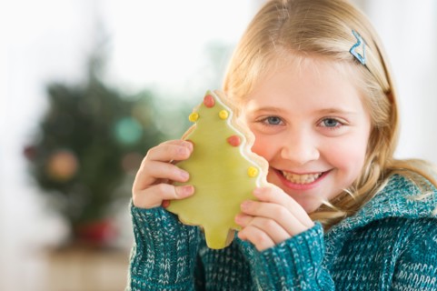 Girl (8--9) holding gingerbread cookie.