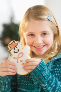 Girl (8--9) holding gingerbread cookie.