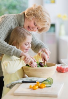Grandmother and granddaughter (8-9) preparing salad together.