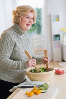 Senior woman preparing salad .