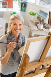Portrait of senior woman painting on canvas.